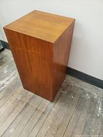 Front angle view of teak pedestal showing square monolithic form