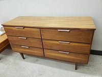 Full front view of the dresser showing six drawers and tapered legs