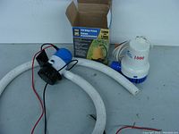 Two boat bilge pumps side by side, one yellow Power Fist pump and one blue Shoreline pump with attached wiring and hoses visible.