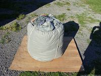 Rolled and tied grey motorhome cover placed on a wooden board outdoors