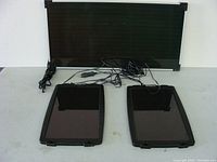 Three solar panels including one large panel and two smaller panels all with cables and connectors on a white surface