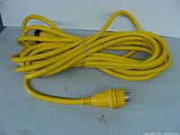 Full view of yellow 50 ft shore power cord coiled with male plug visible