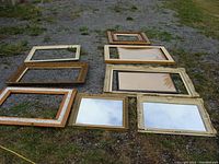 Full group layout of 8 picture frames and 2 mirrors displayed outdoors on grass and gravel.