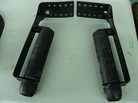 Photo showing front view of one black metal boat trailer guide with two upright padded rollers and multiple mounting holes in the frame.