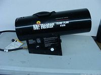 Side view of the black cylindrical Mr. Heater construction heater showing brand name, heat output rating, and carry handle.
