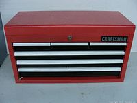 Front view of the closed red Craftsman tool box showing five drawers with white handles and central lock with keyhole.