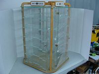 Full view of hexagonal glass display cabinet with wooden frame and multiple glass shelves, placed on a white backdrop.
