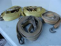 Three heavy duty tie down straps coiled with metal hooks and ratchets visible.