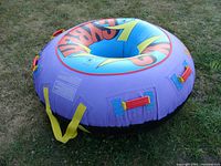 View of inflated Hydro Force snow tube in purple with multicolor branding and handles on grass.