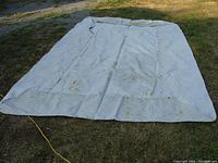Full view of laid out pontoon boat cover showing overall size and condition with visible stains and grommets.