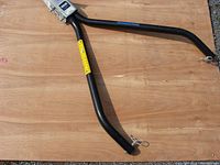 Full view of the black metal Reese tow bar laid on a wooden surface showing the V-shaped frame and attachment points with clips.