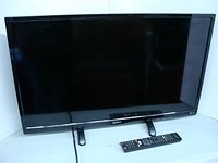 Front view of Seiki 32-inch TV on stand with remote in front.