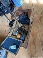 Top view showing all items in the wooden toolbox and a cardboard box, including the cat doorstop, flat iron, apple peeler, alarm clock, soap holder, and old wooden toolbox.