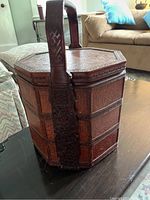 Photo showing full view of the three tier octagonal dowry box with carved handle and woven exterior