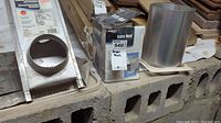 Three dryer vent parts including a metal vent piece, box labeled Deflecto Extra Heat 540 energy saving dryer part, and a rectangular metal vent piece with circular opening.