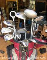 Photo of golf clubs with silver heads in red golf bag showing various club heads and grips.