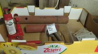 Lot contents showing 1 1/2-ton hydraulic jack and assorted rusty metal parts placed inside a Kiwifruit cardboard box.