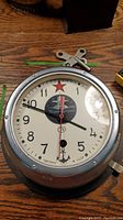 Full view of the Russian submarine clock showing dial, hands, and metal casing.