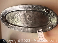 Close-up of the pewter fish platter showing embossed design and surface wear