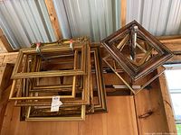 Photo showing multiple stacked and nested picture frames with gold and brown finishes attached with red zip ties.