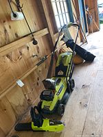 Ryobi cordless lawn mower and 10" chainsaw on wooden floor