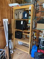 Front view of the wooden shelf showing its five open shelves with various items around it, confirming multiple shelf tiers and structure.