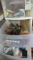 Overall view of the three-drawer plastic storage unit with assorted tools inside each drawer, including bottles, tapes, and hand tools