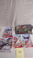 Five sealed Disney Planes toy packages arranged on a light fabric background, including a multi-plane playset and four individual figure packages with visible Disney Planes logos and character images.