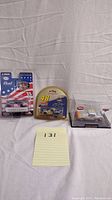 Full view showing all three die-cast toy cars in packaging on a white cloth background with a yellow note marked 131.