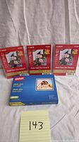 Lot showing three packs of Canon Photo Paper Plus Glossy II and one pack of Staples Photo Plus Gloss Paper on white fabric background.