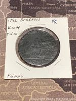 Obverse side of 1792 Barbados penny showing King Neptune in chariot with date 1792 below, mounted in cardboard holder.