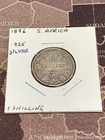 Front side of the 1896 South Africa 1 Shilling coin showing the denomination and decorative design.