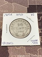 Obverse side showing '50 CENTS 1904' and 'NEWFOUNDLAND' with decorative scrollwork on the coin.
