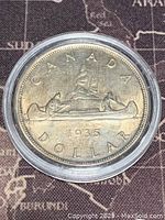 Reverse side of 1935 Canadian silver dollar coin showing voyageur canoeing design and date 1935.
