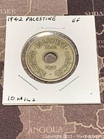 Front side of the 1942 Palestine 10 Mils coin showing year, location in English, Arabic and Hebrew around center hole.