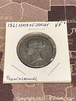 Obverse side of the 1961 State of Jersey 1/26 shilling copper coin, showing Queen Elizabeth II's profile and handwritten notes on cardboard holder.