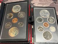 Two black cases open showing complete 1978 and 1980 Canadian silver double dollar proof sets with multiple coins each including the large double dollar coin
