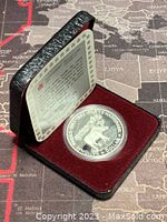 Photo of the open black case with red velvet lining and Canadian silver coin inside, showing certificate insert.