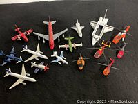 Top view showing all 15 die cast airplanes, jets and helicopters in various colors and sizes on a black background.