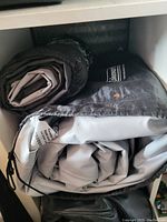 Photo of two rolled blow-up air mattresses on a shelf, one branded Coleman.