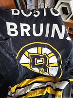 Photo of a black fleece blanket featuring the Boston Bruins logo and team colors.