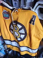 Vintage Boston Bruins yellow hockey jersey showing Bruins logo, North Classic patch, and 'A' shoulder patch.