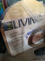 Photo of packaging showing product name and brand 'forLIVING' bamboo laundry hamper with product features.
