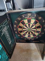 Dartboard inside wooden cabinet with scoring on left door