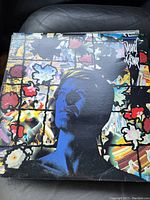 Front cover of a David Bowie vinyl record featuring a blue-toned portrait of the artist in front of stained glass floral artwork.