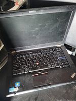 Opened Lenovo ThinkPad laptop keyboard and screen showing wear and keyboard with TrackPoint.