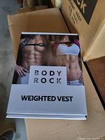 Boxed weighted vest packaging with fitness model images on the front, labeled BodyRock Weighted Vest.