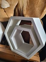 Three white hexagonal wall hanging shelves in different sizes stacked together.