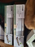 Two KidKraft Easy to Life white wall shelves in original boxes showing product branding, size, and support load.