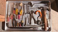 All assorted hand tools laid out on metal tray including hammers, screwdrivers, pliers, wrenches, tape and more